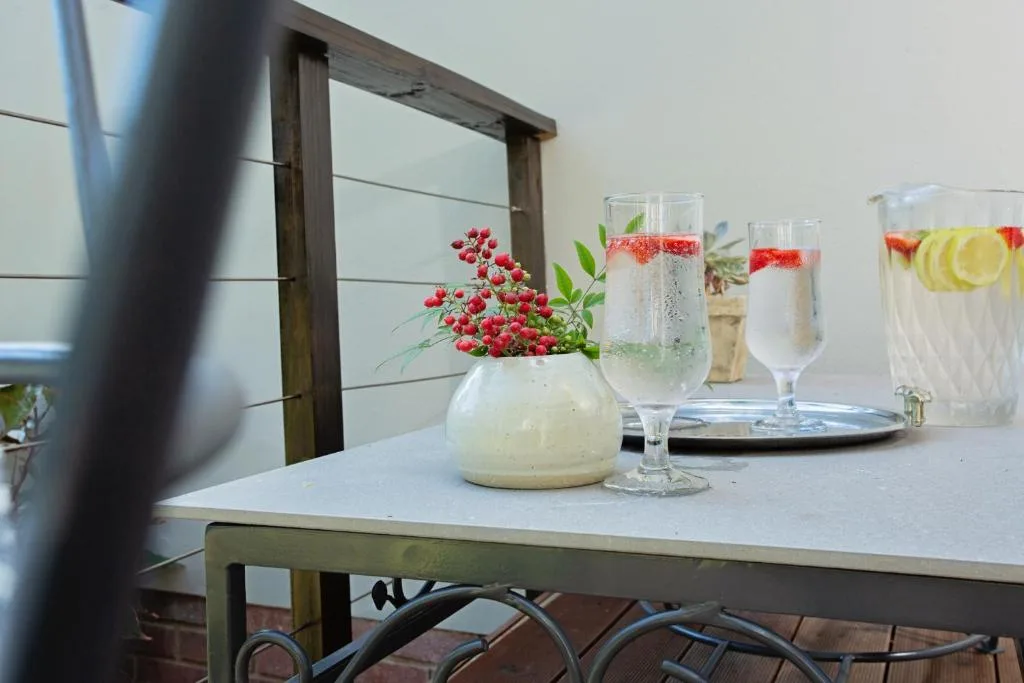 Outdoor table with refreshing beverages and red berry flower arrangement