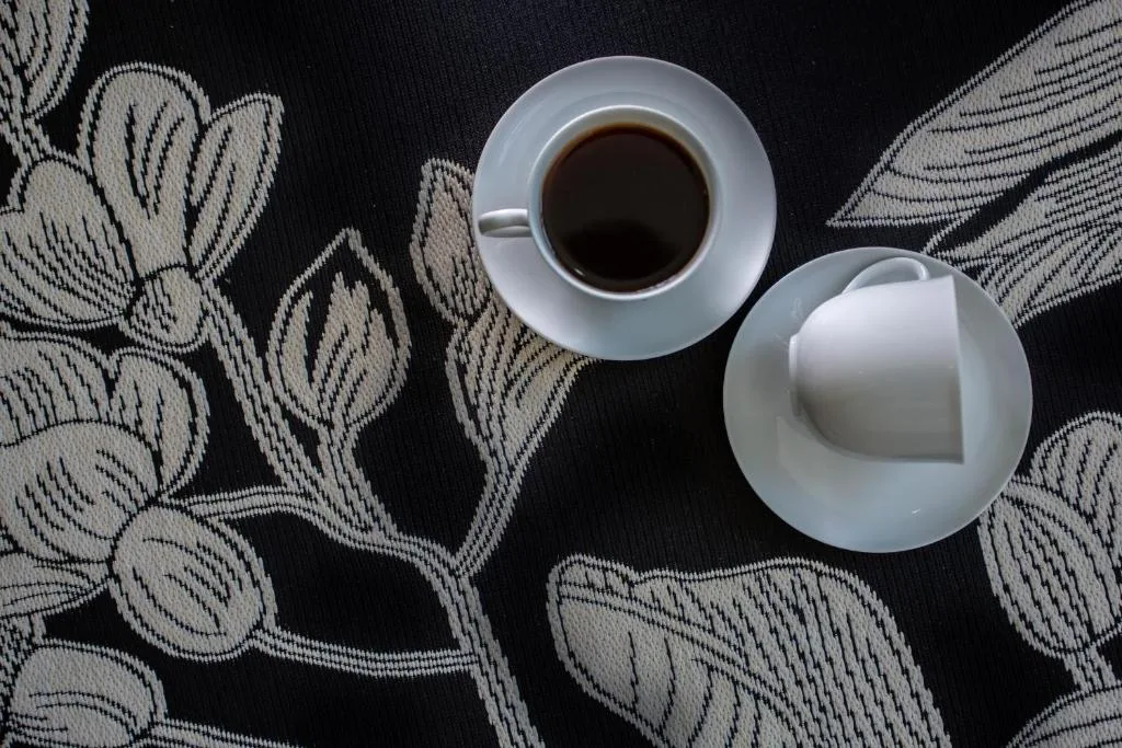 Coffee cup and saucer on patterned black and white fabric