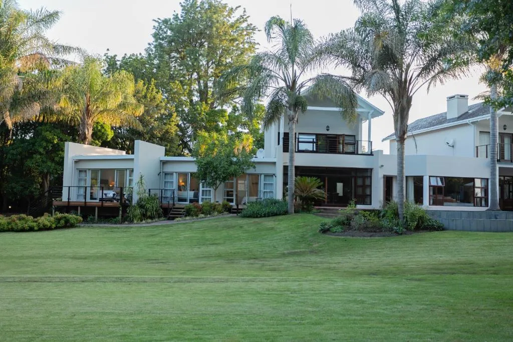 Modern white house with manicured lawn and mature palm trees surrounding