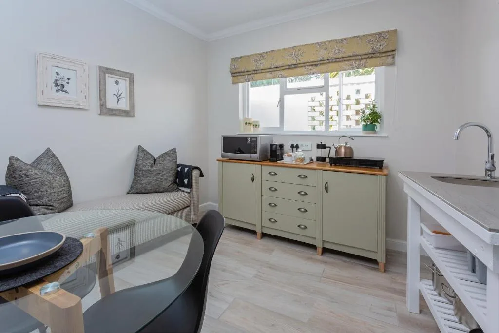 Open-plan kitchenette with pale green cabinetry, wooden countertop, and modern appliances