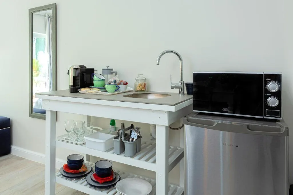 Compact kitchenette with sink, microwave, and open shelving storage
