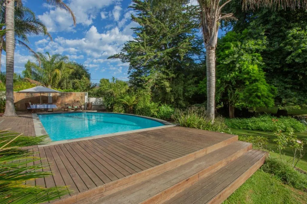Sparkling blue swimming pool with wooden deck and tropical garden surroundings