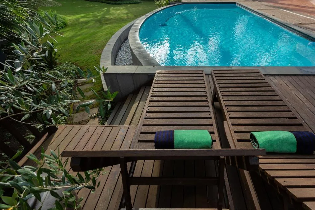 Swimming pool with turquoise water and wooden sun loungers on deck
