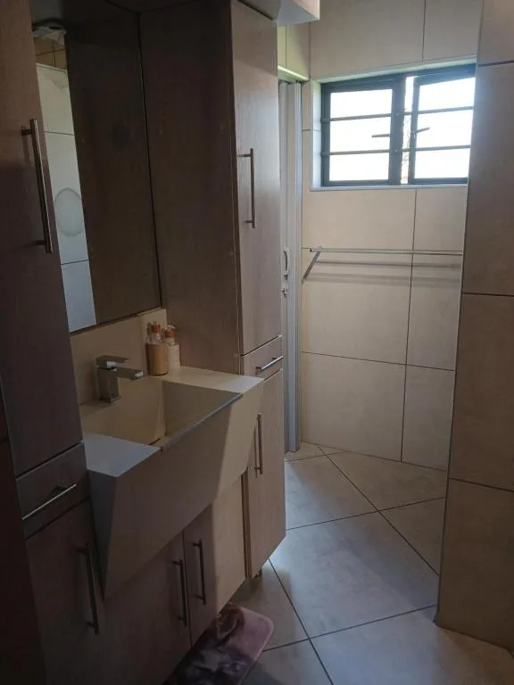 Modern bathroom with vanity sink, large mirror, and tiled shower enclosure