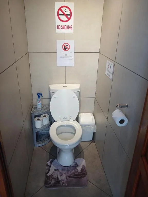 Compact toilet cubicle with white porcelain toilet and no smoking sign displayed