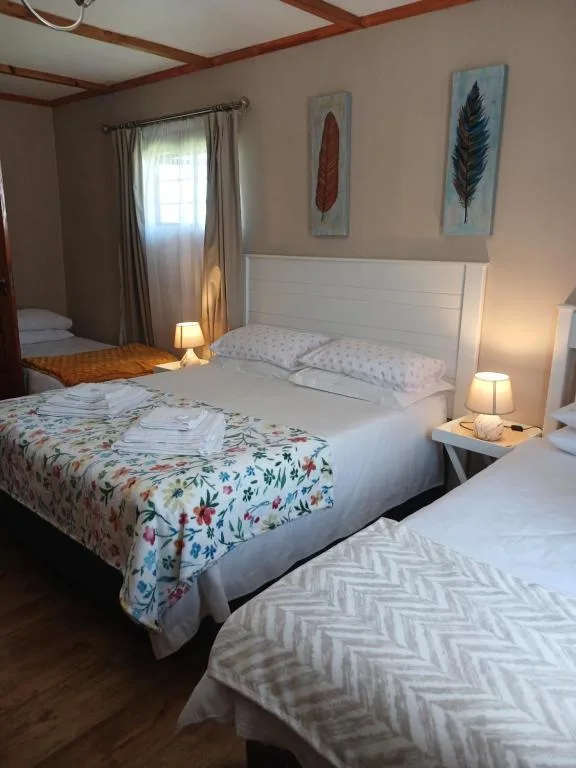 Bright bedroom with two beds, white headboards, floral bedding and side lamps