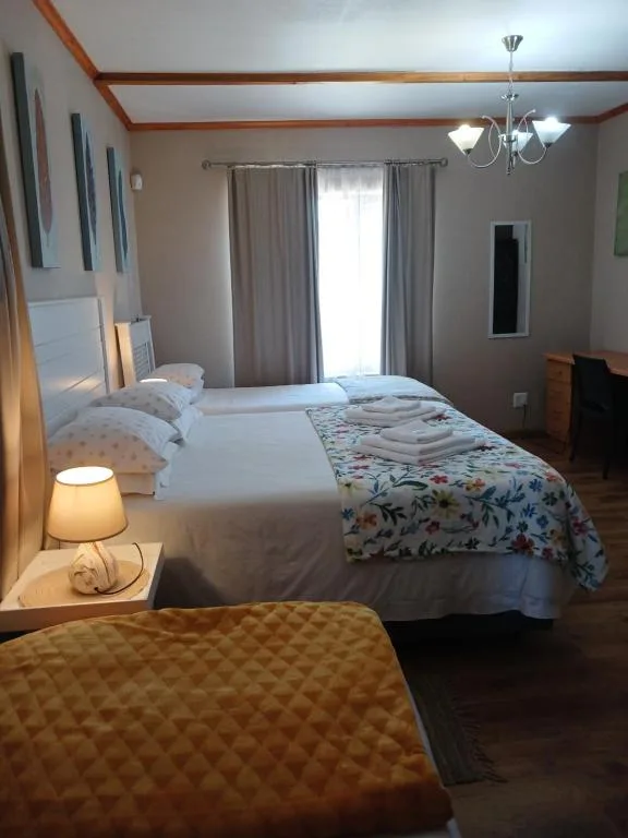 Spacious bedroom with double bed, wooden beams, and bright windows