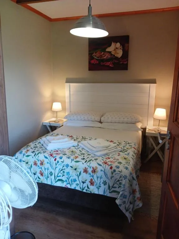 Bedroom with floral patterned duvet, white headboard, pendant light fixture