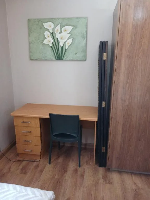 Wooden desk with chair and floral artwork on white wall