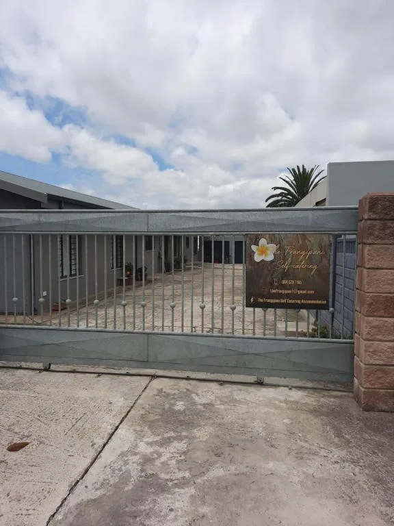 Modern self-catering property entrance with metal gate and palm tree