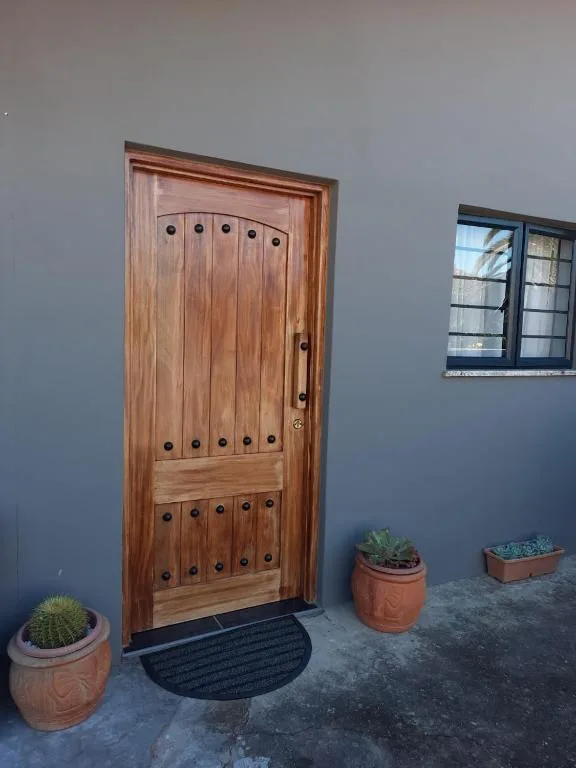 Wooden entrance door with iron studs and potted succulents outside