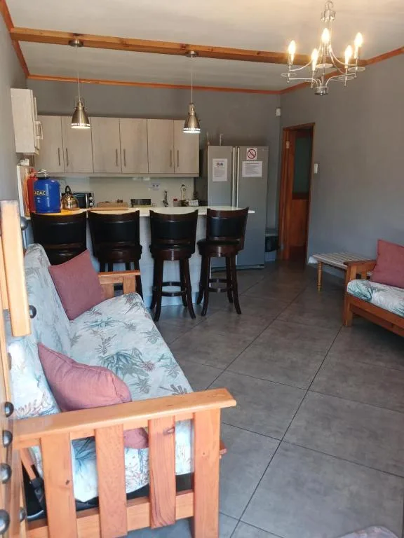 Open-plan lounge with sofa, kitchen counter seating, and pendant lighting