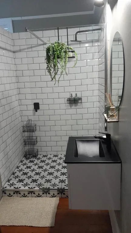 Modern bathroom with white subway tiles, black vanity, and hanging green plant