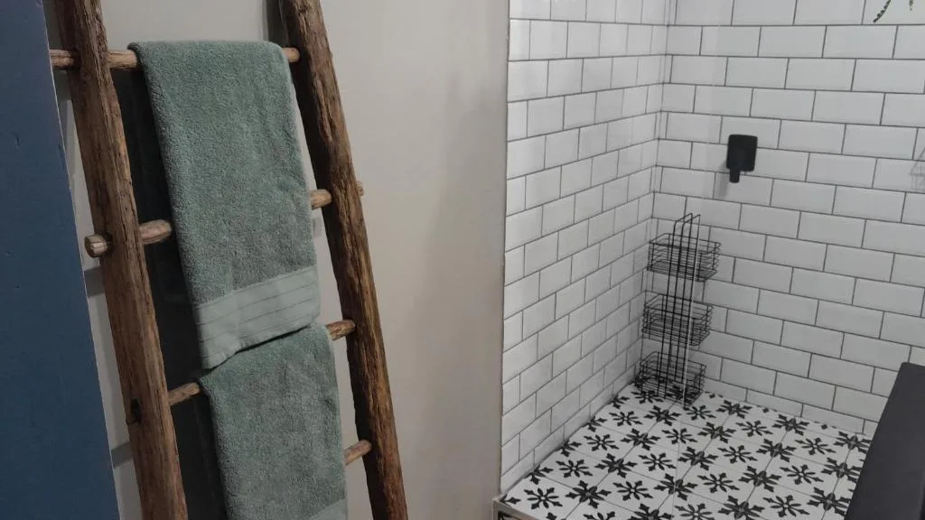 Modern bathroom with white subway tiles, patterned floor, and rustic wooden towel ladder
