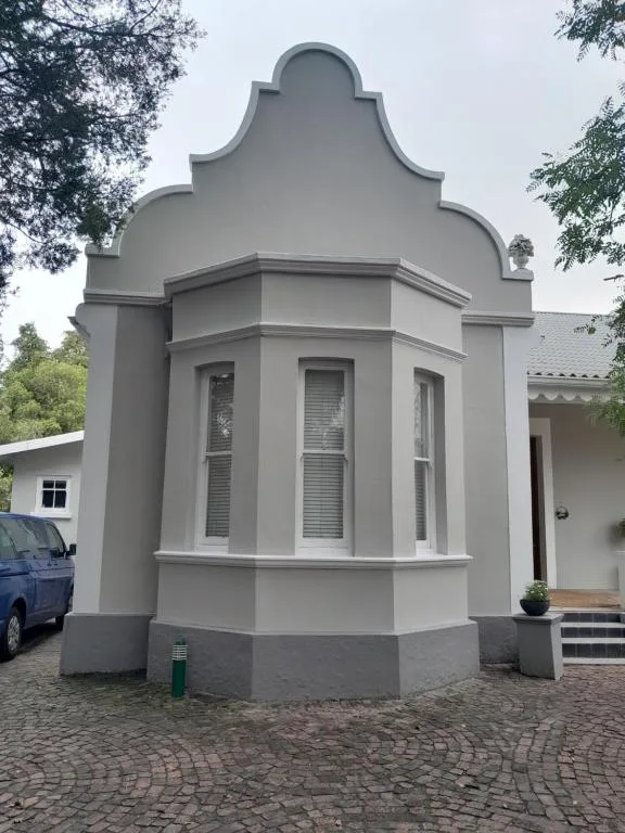 Distinctive octagonal white building with architectural crown detail and brick driveway