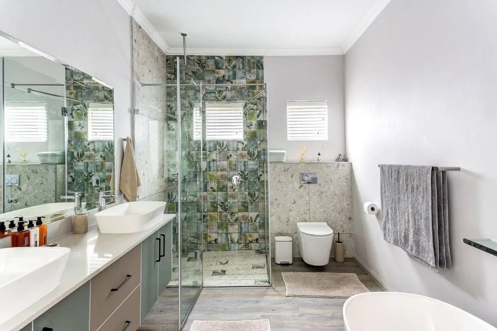 Modern bathroom with walk-in shower, dual vanity, and botanical tile accents