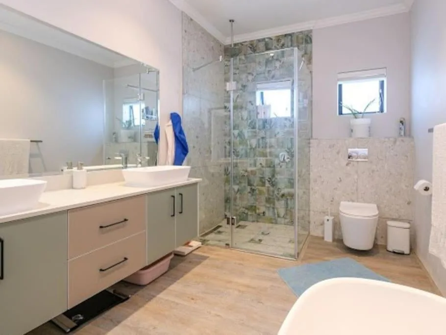 Modern bathroom with vanity, toilet, and large walk-in shower enclosure