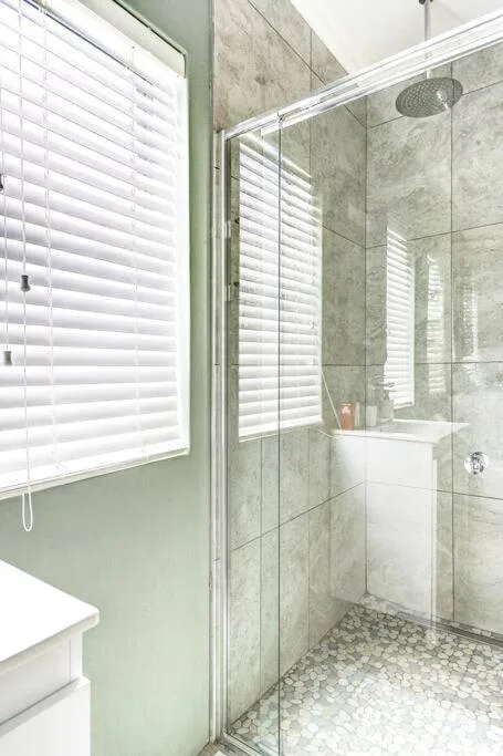 Modern bathroom with marble tiles, glass shower enclosure, rainfall showerhead