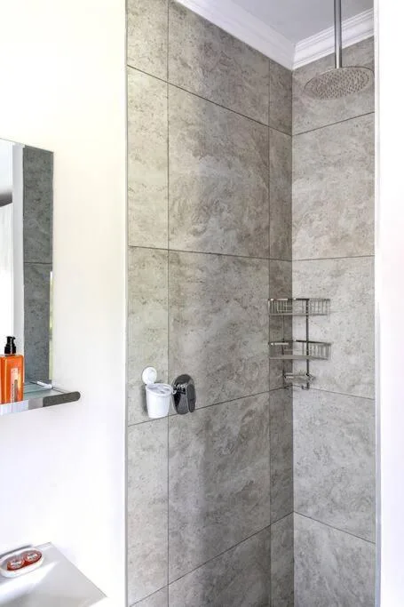 Modern shower enclosure with grey tile walls and rainfall showerhead