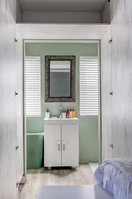Ensuite bathroom with white vanity, framed mirror, and green accent walls