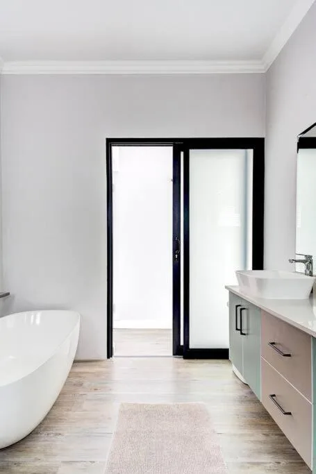 Modern bathroom with freestanding tub, vanity, and glass doors