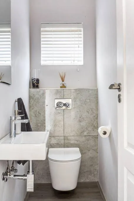 Modern bathroom with white sink, toilet, and grey tiled wall paneling