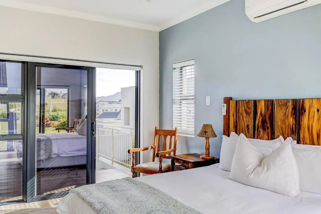 Spacious bedroom with white bedding, wooden headboard, and sliding glass doors to deck