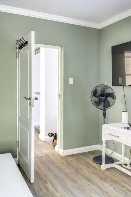 Bedroom with sage green walls, white door, and wooden flooring