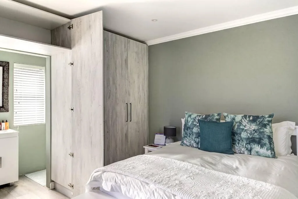 Modern bedroom with queen bed, green walls, built-in wardrobe, ensuite bathroom
