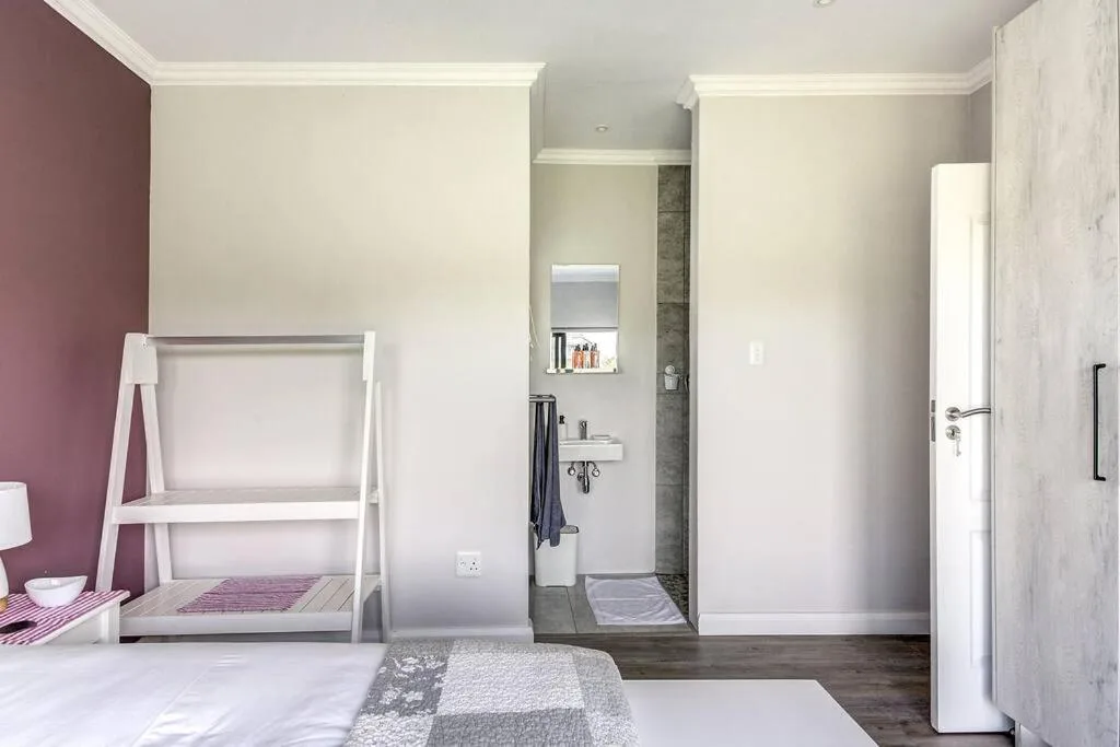 Modern bedroom with ensuite bathroom, purple accent wall, and contemporary furnishings