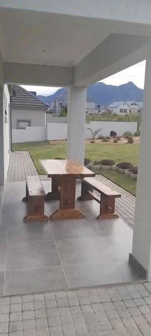 Covered patio with wooden picnic table overlooking manicured garden and mountains