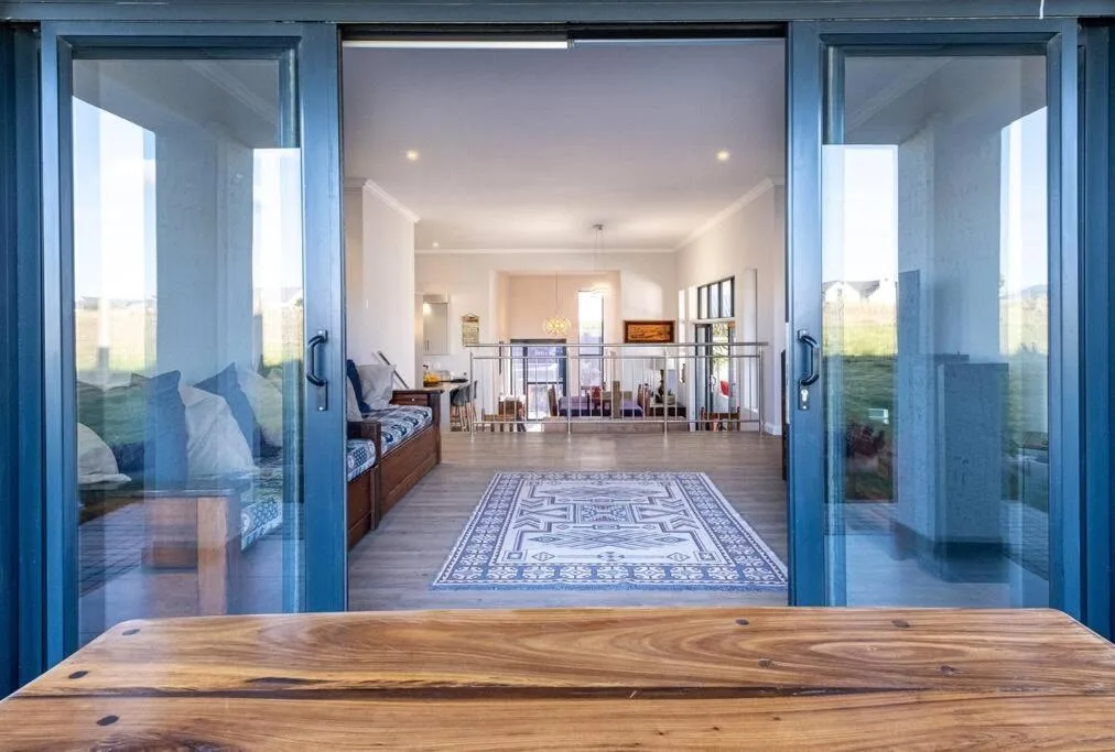 Open blue sliding glass doors lead to spacious wooden deck with countryside views