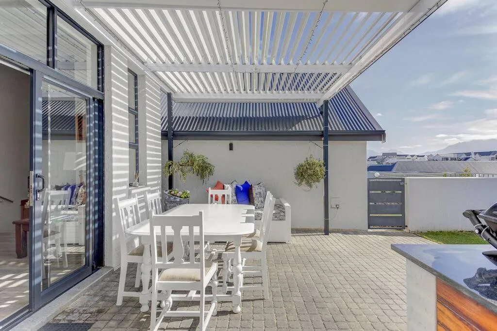 Modern covered patio with white dining table and chairs overlooking garden