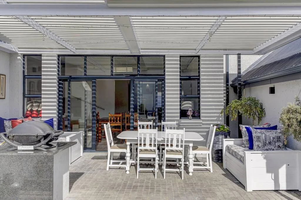 Spacious outdoor patio with dining table, lounge seating, and braai area