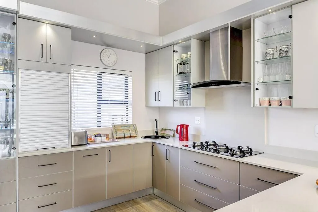 Modern kitchen with gas stove, white cabinetry, and stainless steel hood