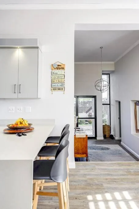 Modern white kitchen with island seating and open-plan living area