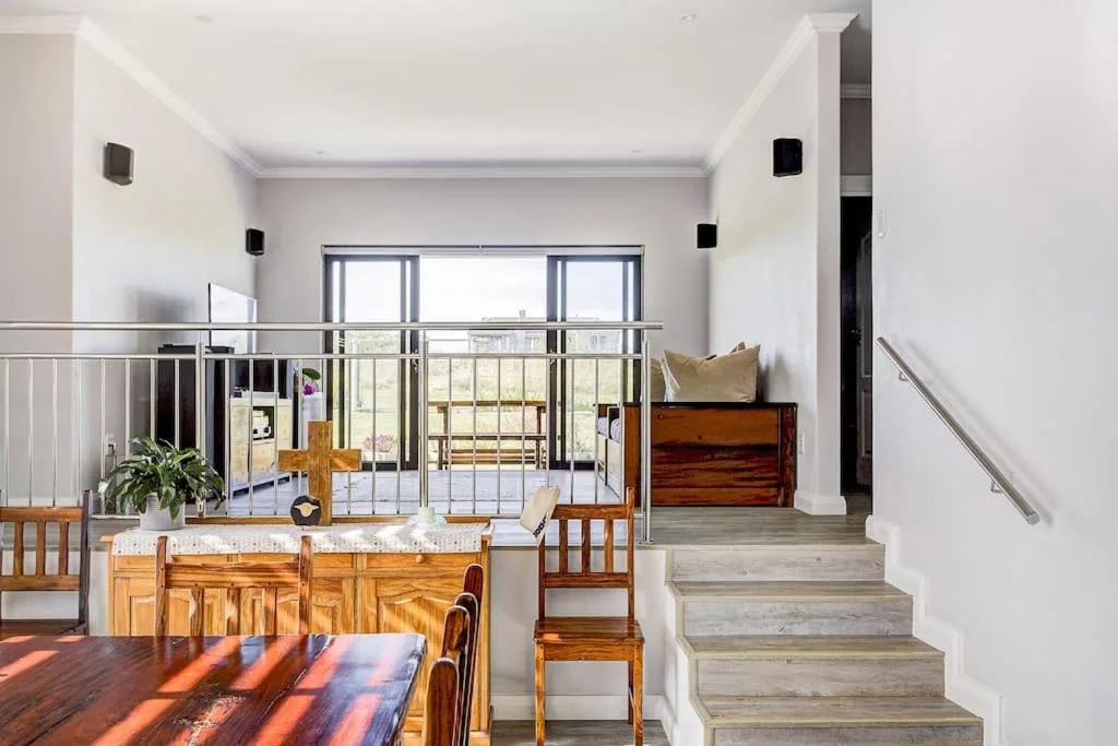 Open-plan lounge with wooden dining table and staircase access to upper level