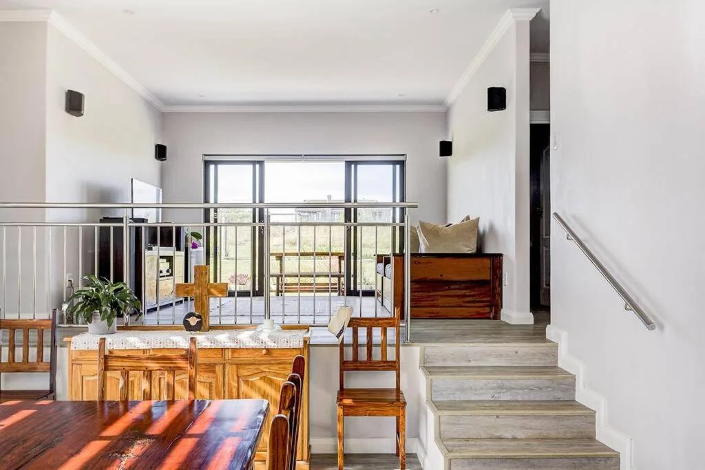 Open-plan living space with wooden dining table and modern staircase leading upward