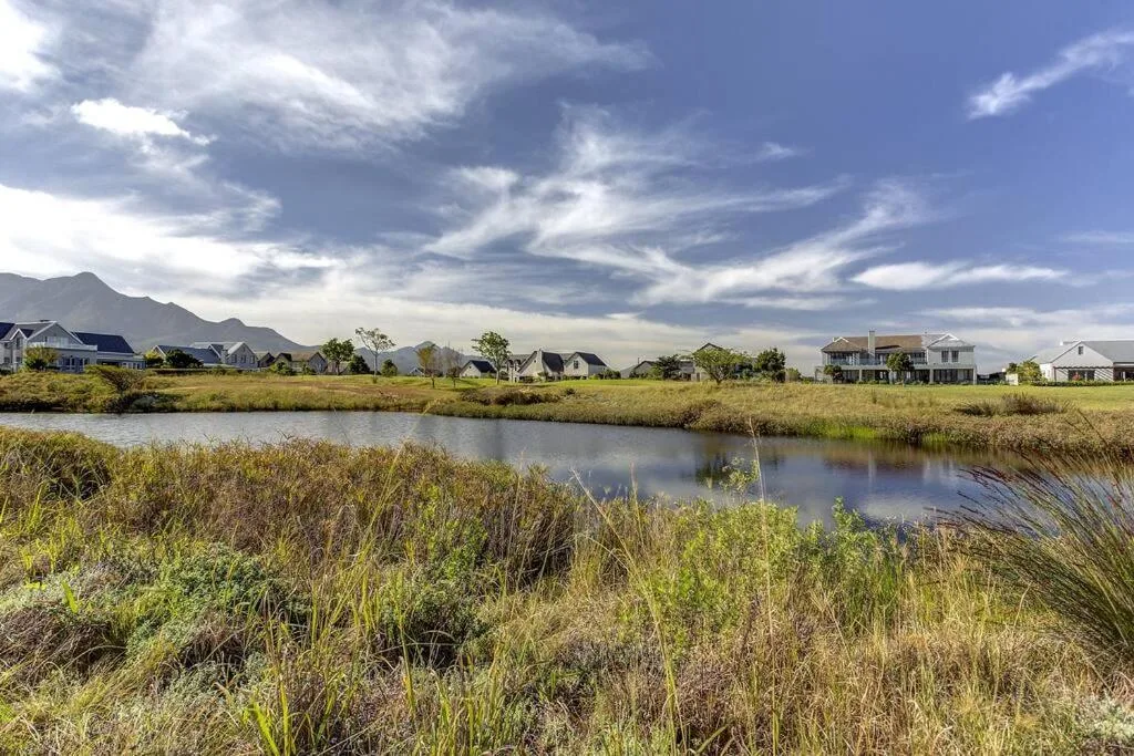 Scenic waterfront view of residential properties with mountains and dramatic sky