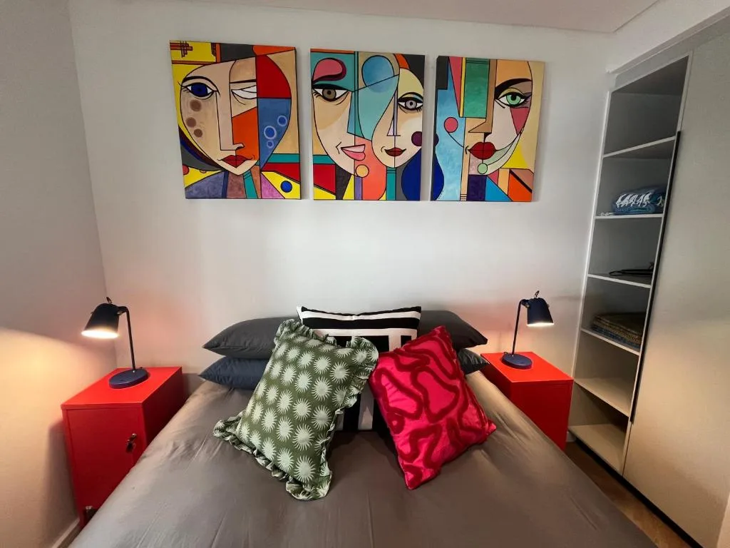 Modern bedroom with colorful abstract art above bed and red nightstands