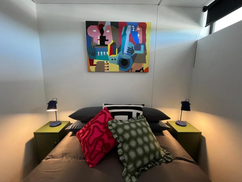 Modern bedroom with colorful abstract artwork above bed and styled pillows