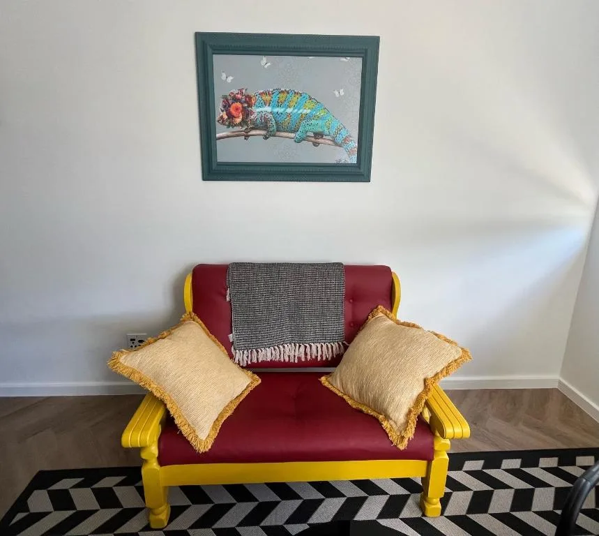 Colorful upholstered seating with decorative pillows and framed chameleon artwork
