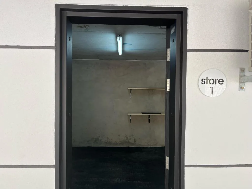 Glass-fronted storage closet with shelving and store signage on white wall