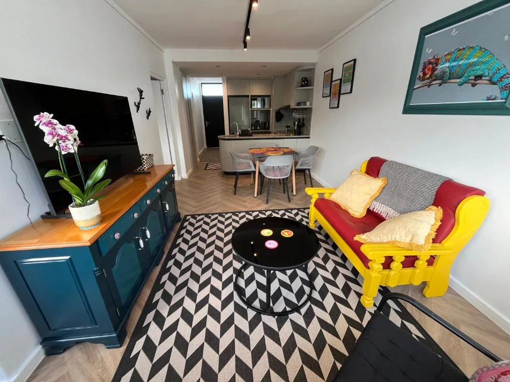 Bright open-plan lounge with colorful yellow chair and dining area beyond