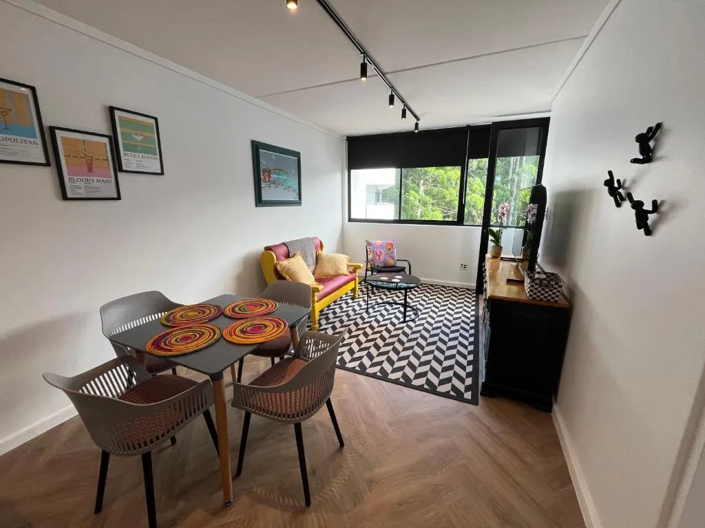 Modern lounge with dining table, colorful seating, and garden views