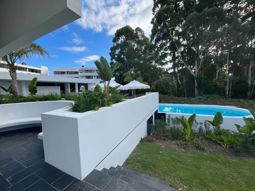 Modern swimming pool with landscaped garden and forested backdrop