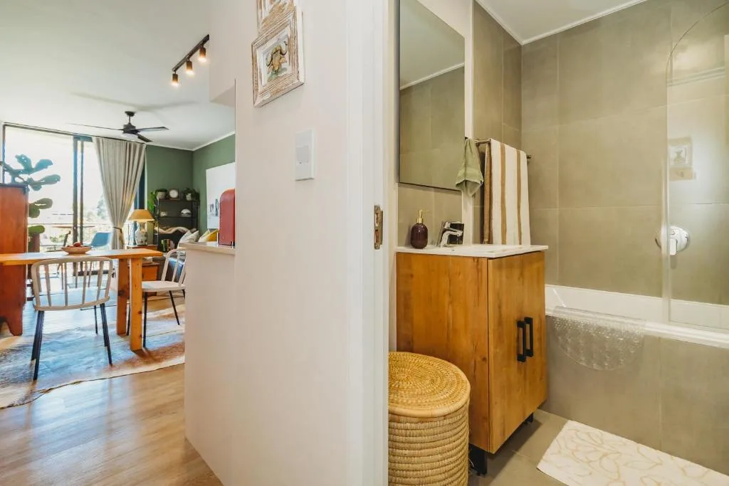 Modern bathroom with wooden vanity, green tiled walls, and glass shower enclosure