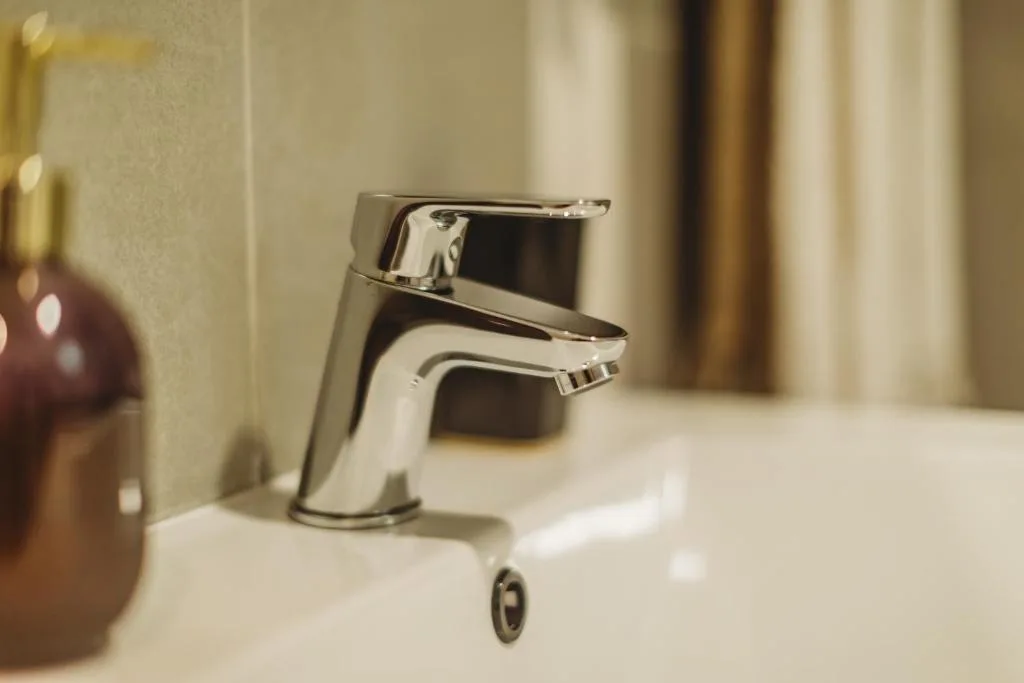 Modern chrome basin tap on white vanity with soft lighting