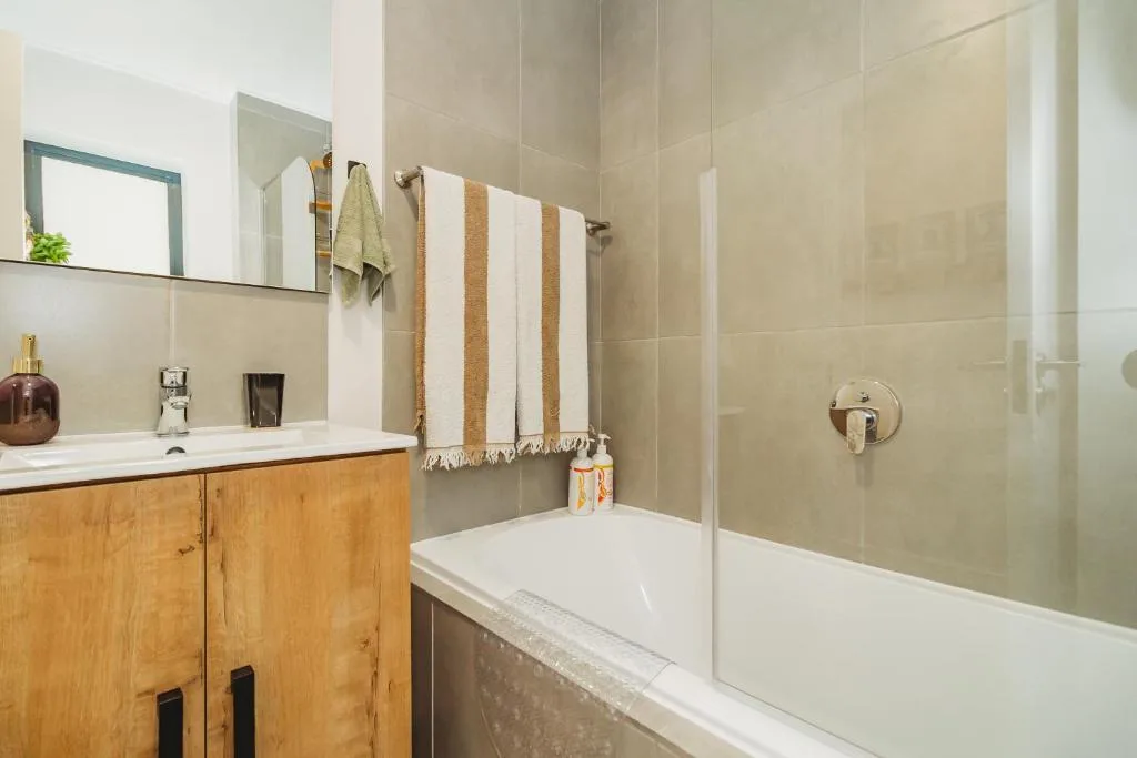 Modern bathroom with wooden vanity, white sink, and glass shower enclosure