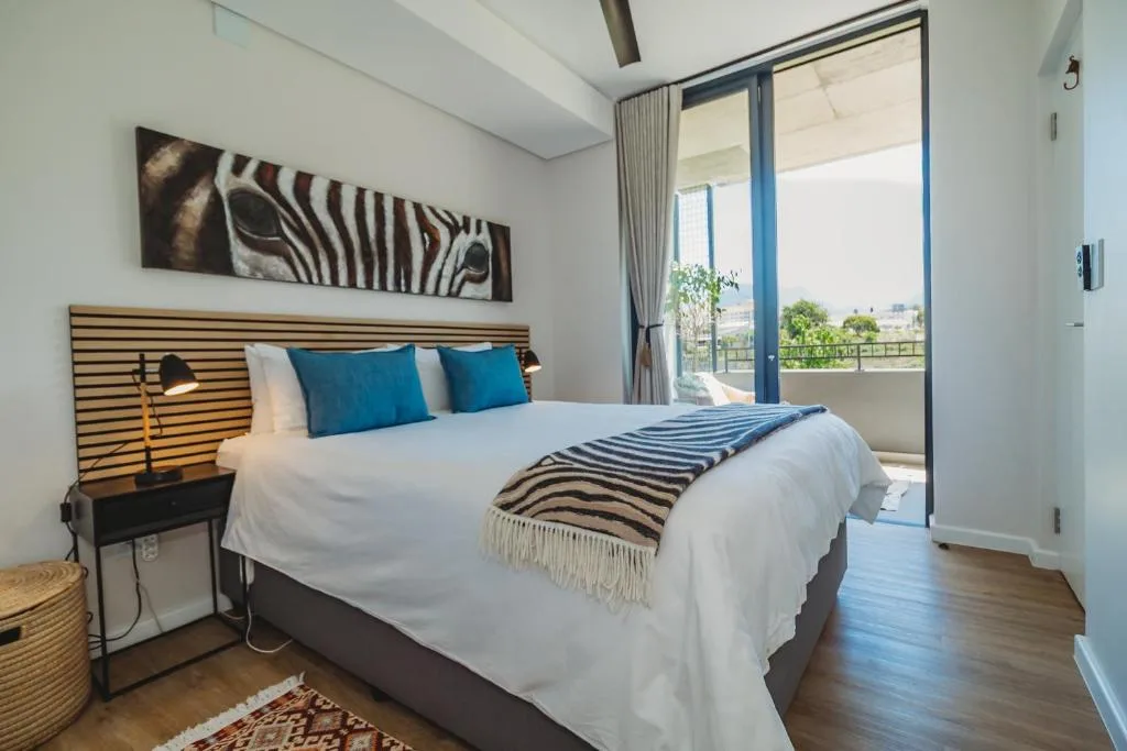 Modern bedroom with queen bed, blue pillows, zebra artwork, and sliding glass doors
